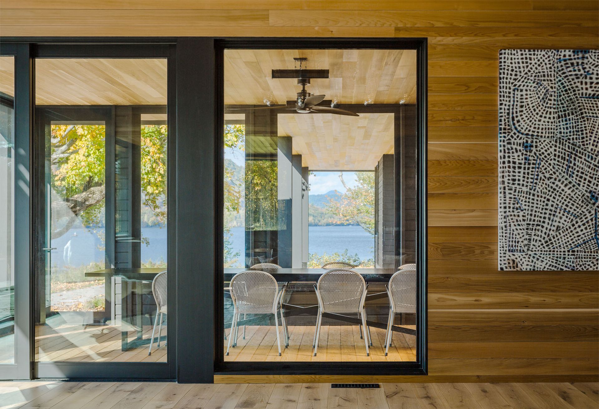 A dining room with a table and chairs and a large window overlooking a lake.
