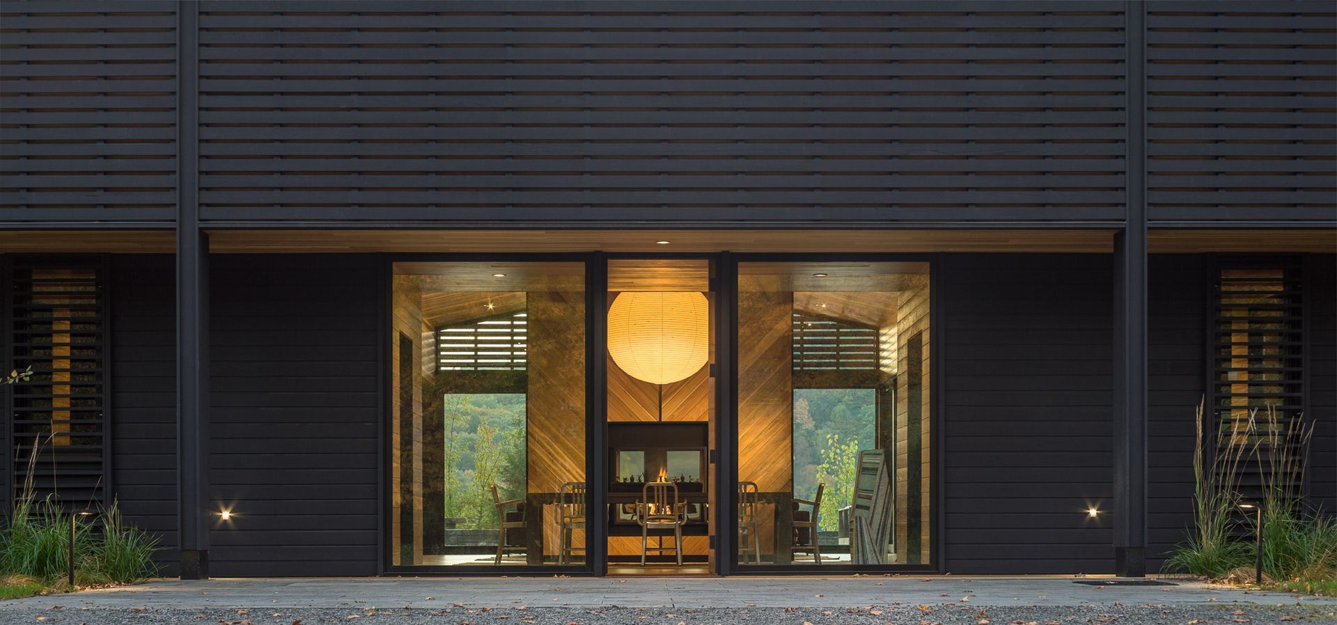 A large black building with a lot of windows and a lantern hanging from the ceiling.