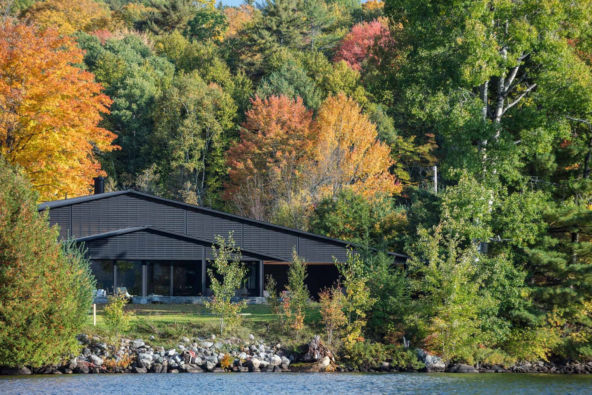 A house is sitting on the shore of a lake surrounded by trees.