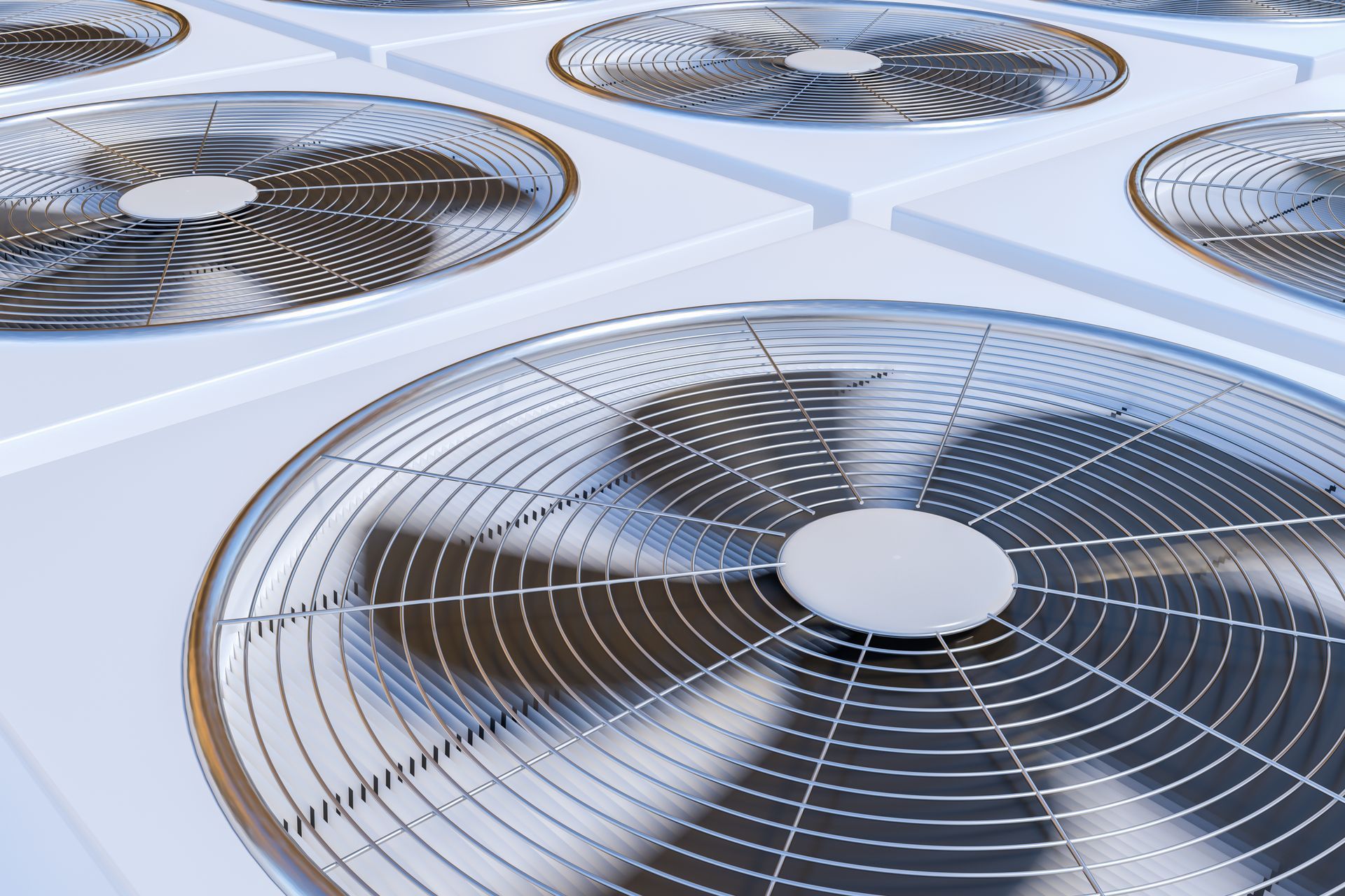 Close-up of multiple air conditioning units, with large fan blades behind protective metal grilles.