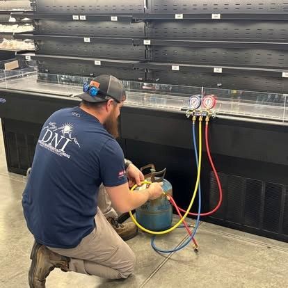 Person using a wrench to work on electrical components inside an HVAC unit.