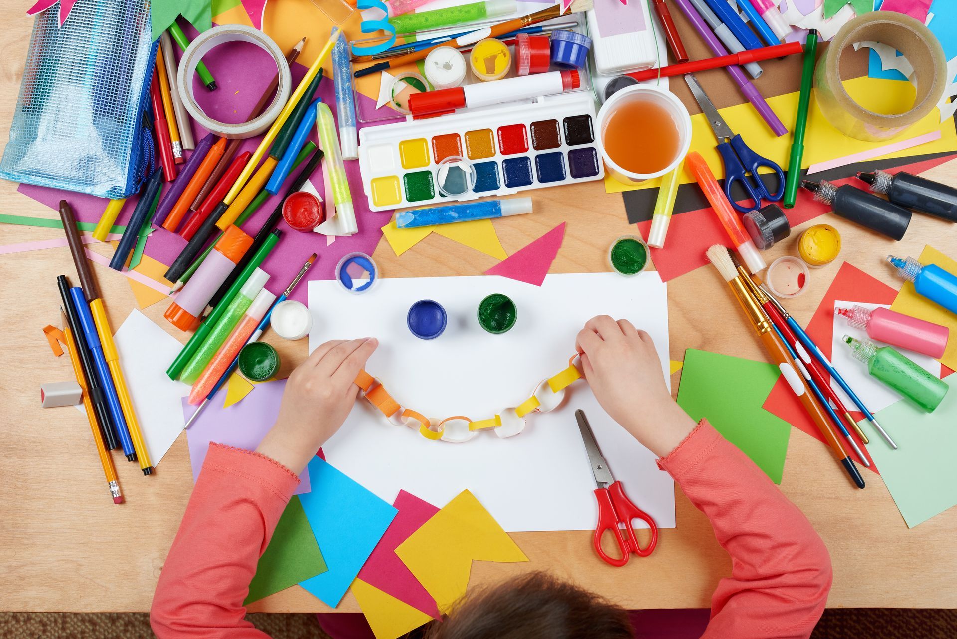 A child is sitting at a table with a bunch of art supplies.
