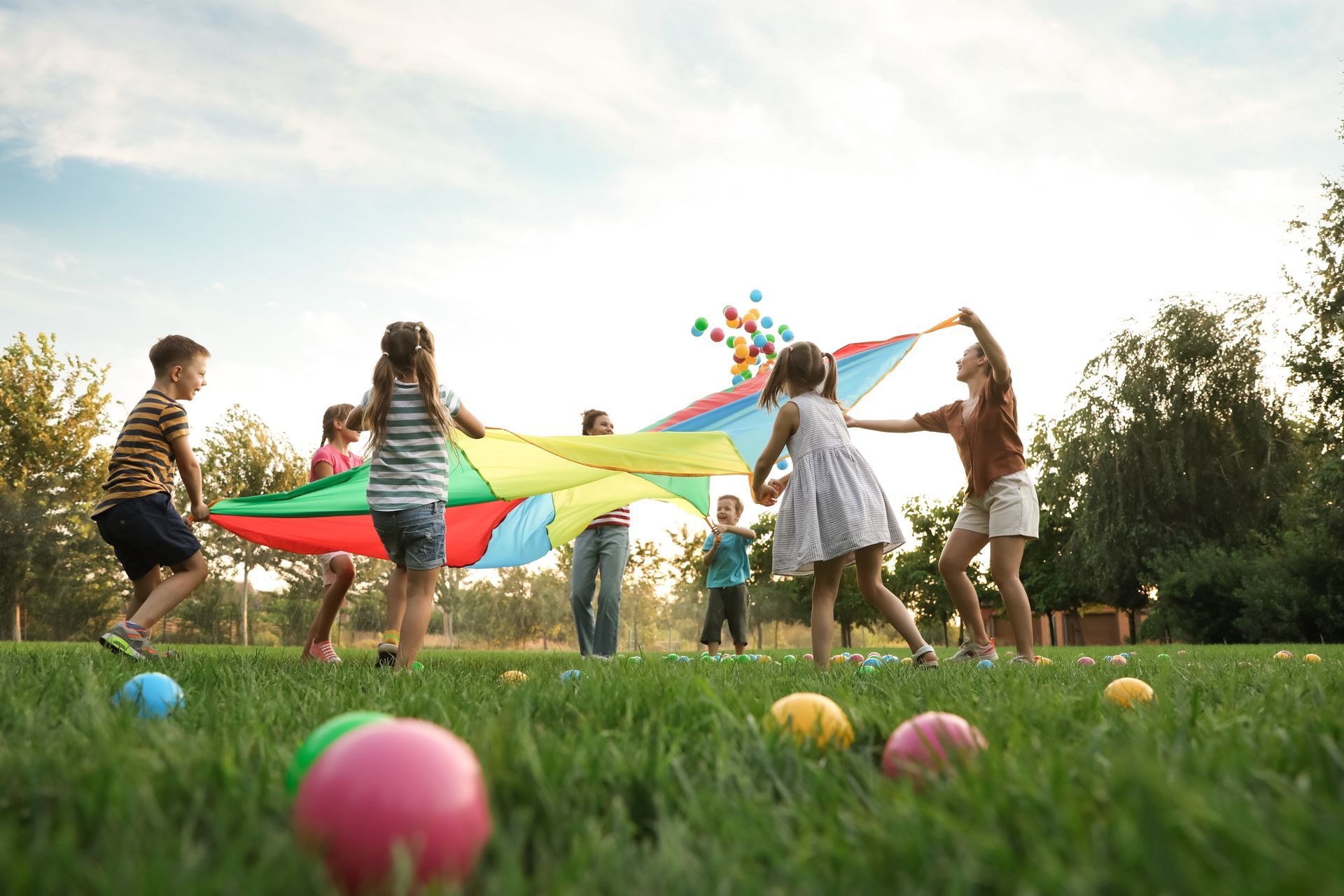 A group of children are playing with a parachute in a park.