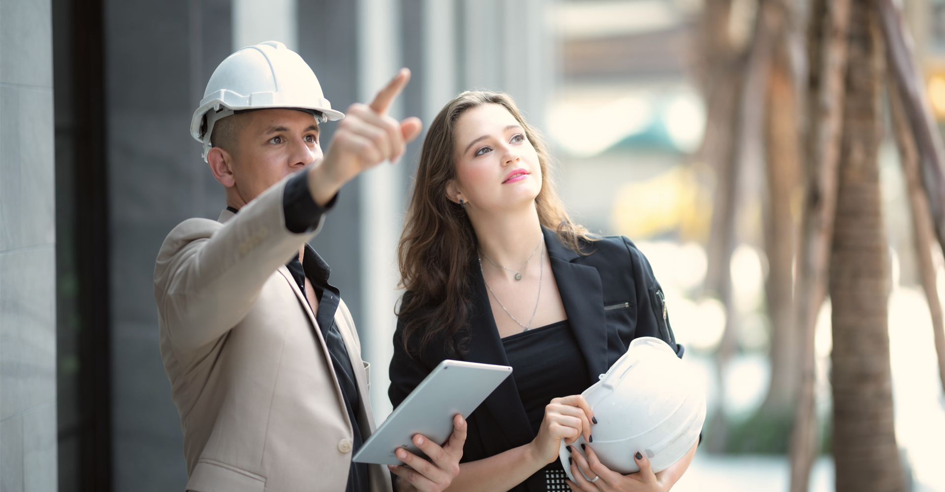 A man and a woman are standing next to each other looking at a tablet.