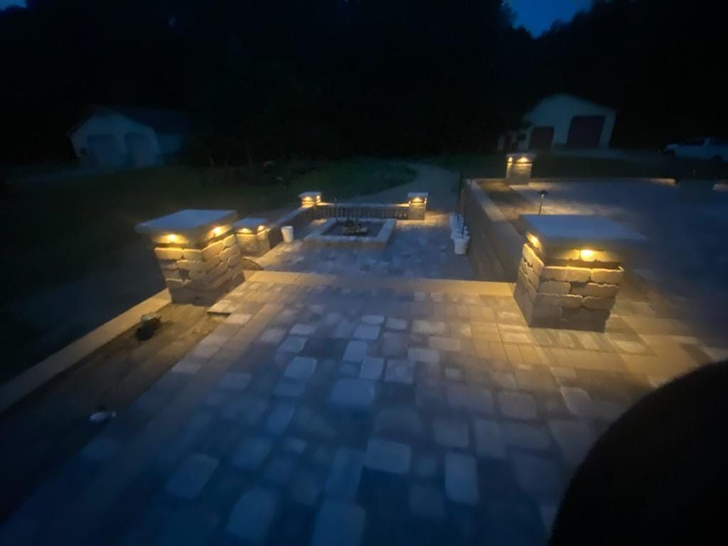 A patio with a fire pit and stairs is lit up at night.