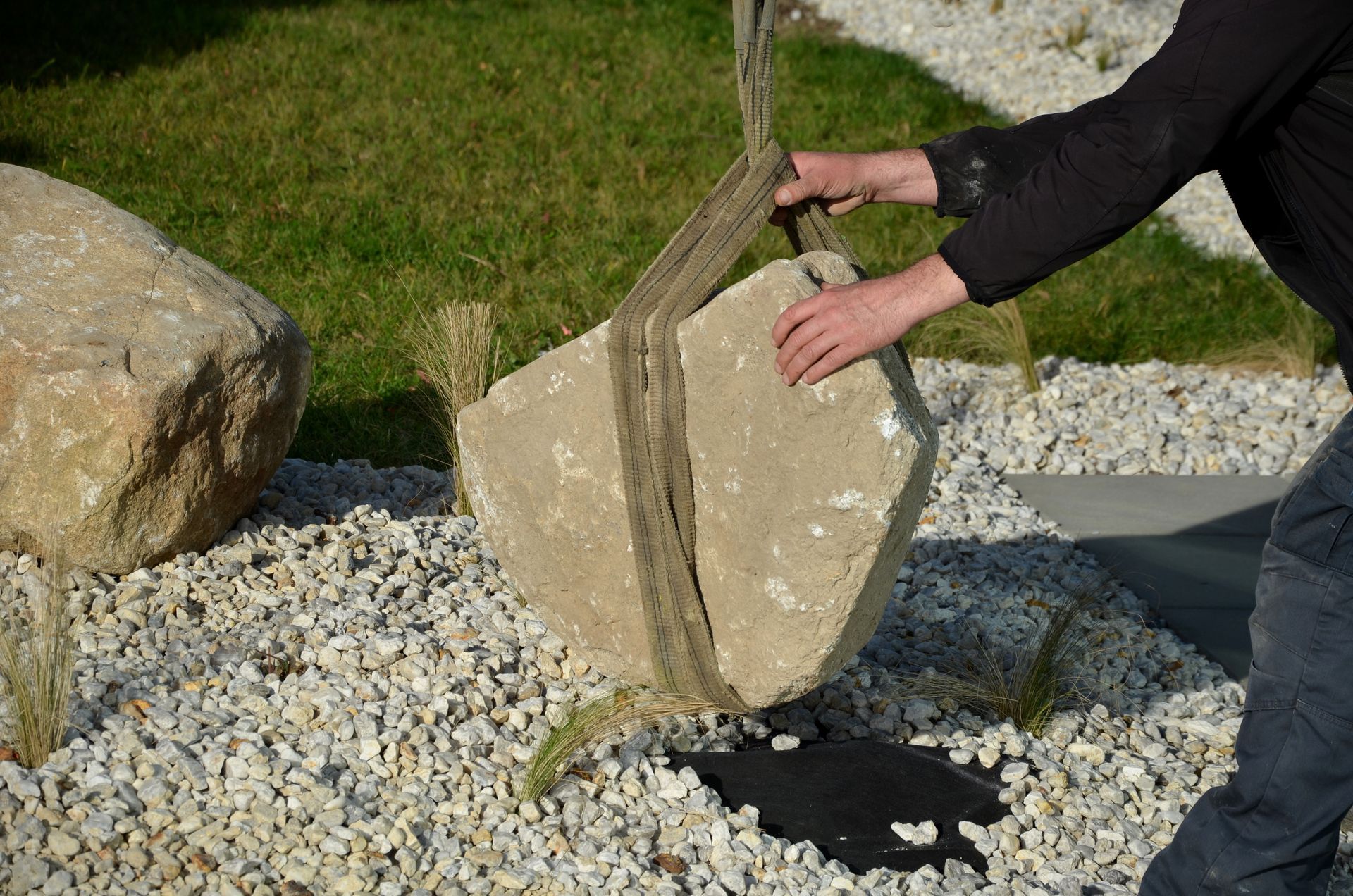 A man is lifting a large rock with a rope.