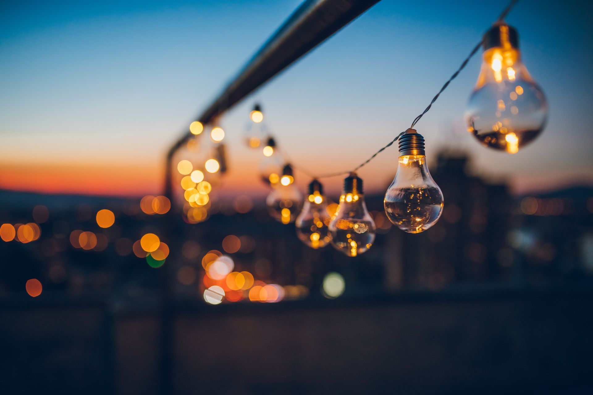A string of light bulbs hanging from a railing at night.