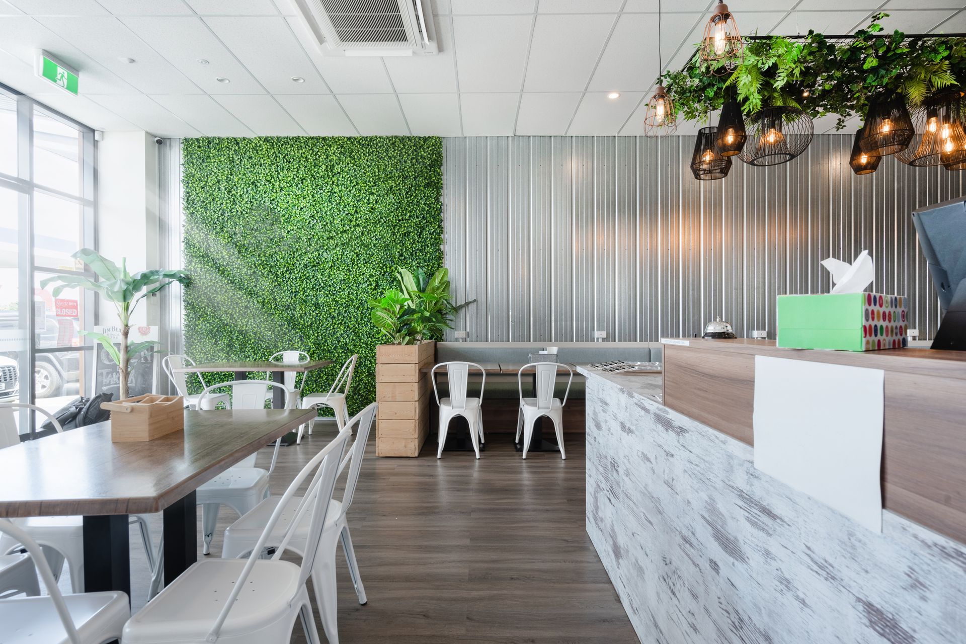 A restaurant with tables and chairs and a green wall.