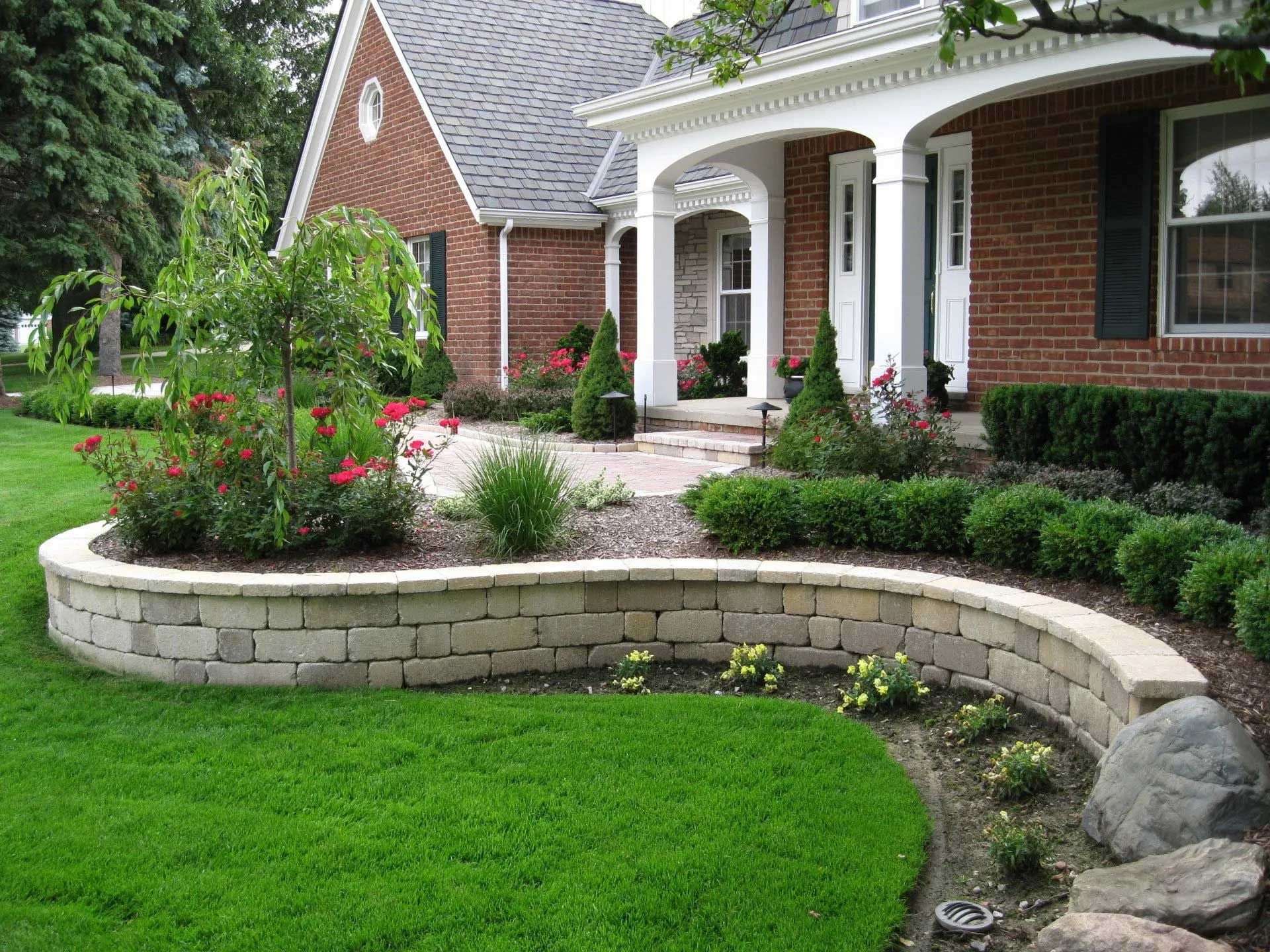 A brick house with a curved stone wall in front of it