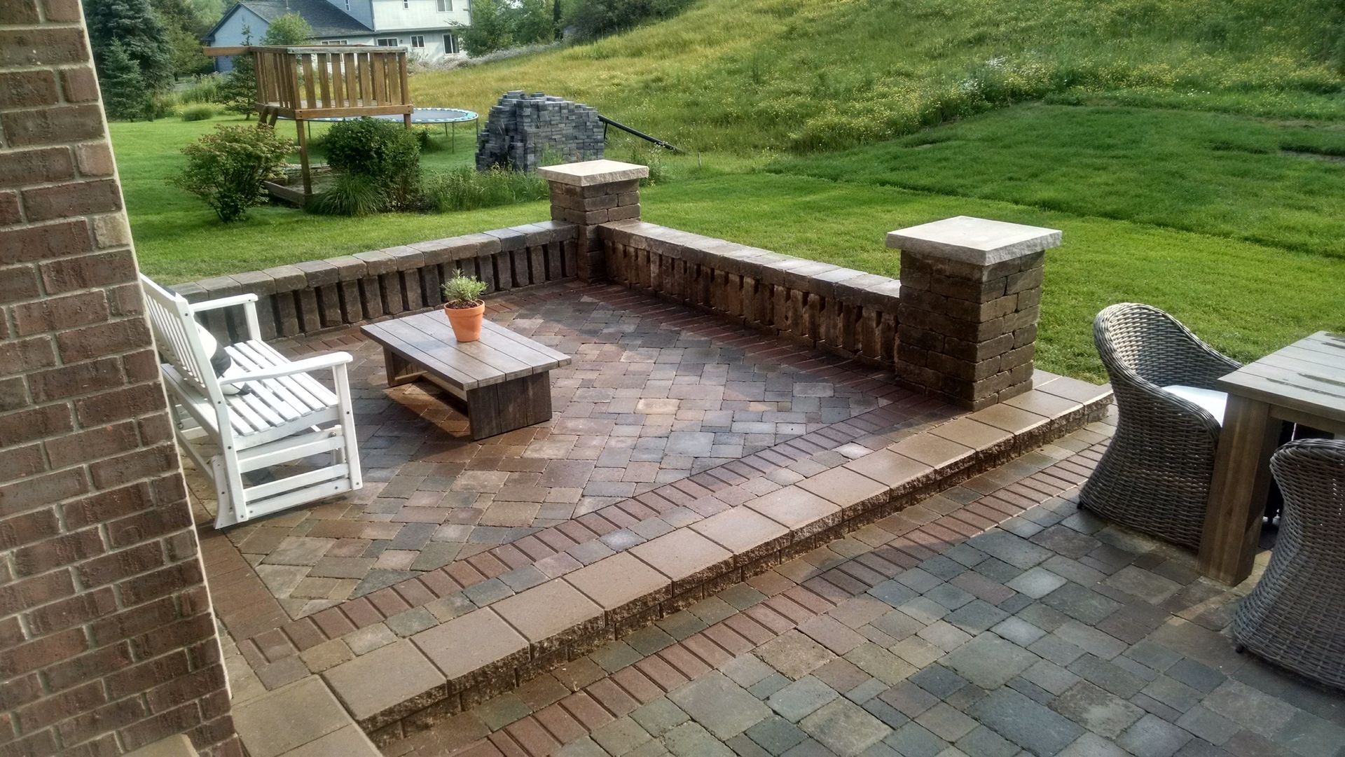Quality retaining wall surrounded by dirt in front of a brick building.