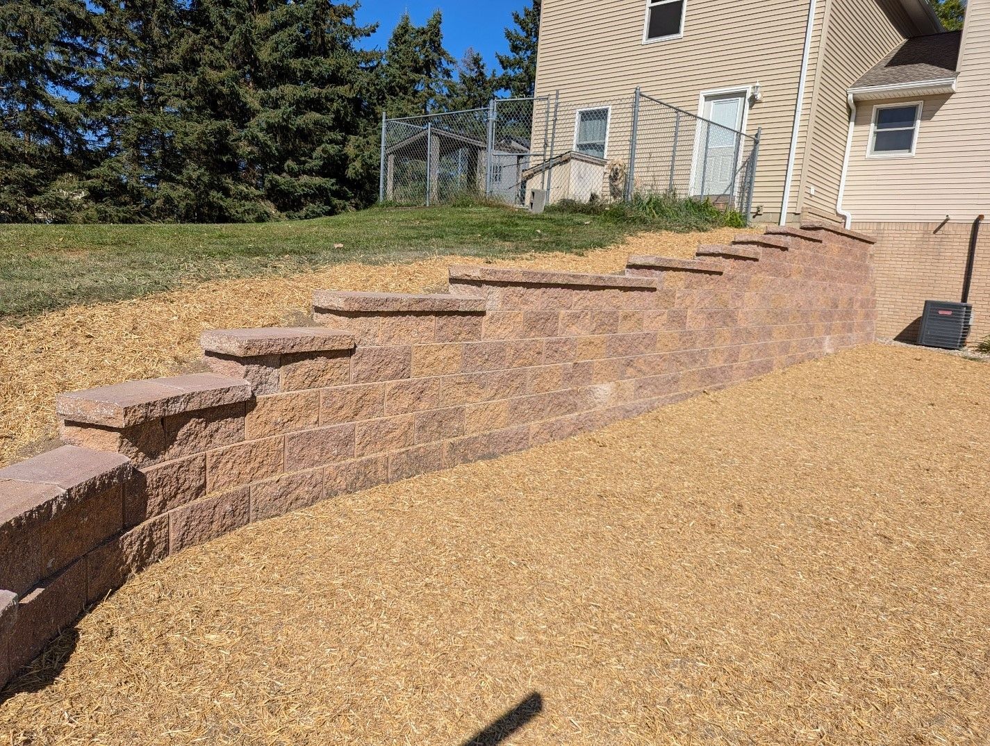 A stone wall with steps leading up to a house.