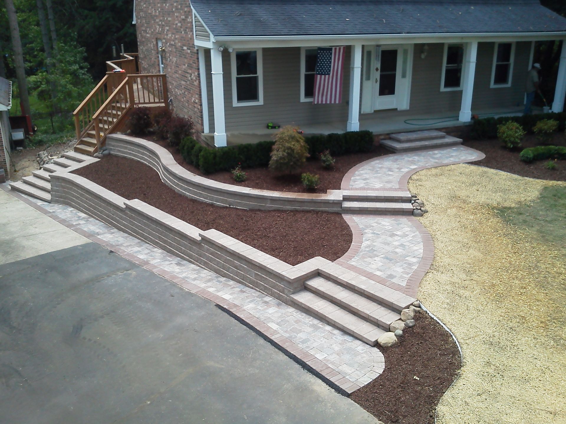 An aerial view of a house with a concrete driveway leading to it and a driveway extensions.