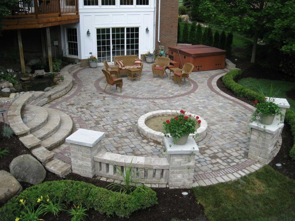 A patio with a fire pit and a hot tub in the backyard of a house