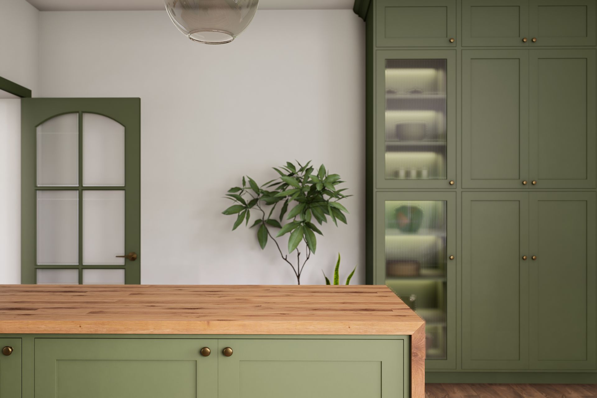 A kitchen island with a wooden countertop in front of olive-green cabinetry and an arched door with glass panels.