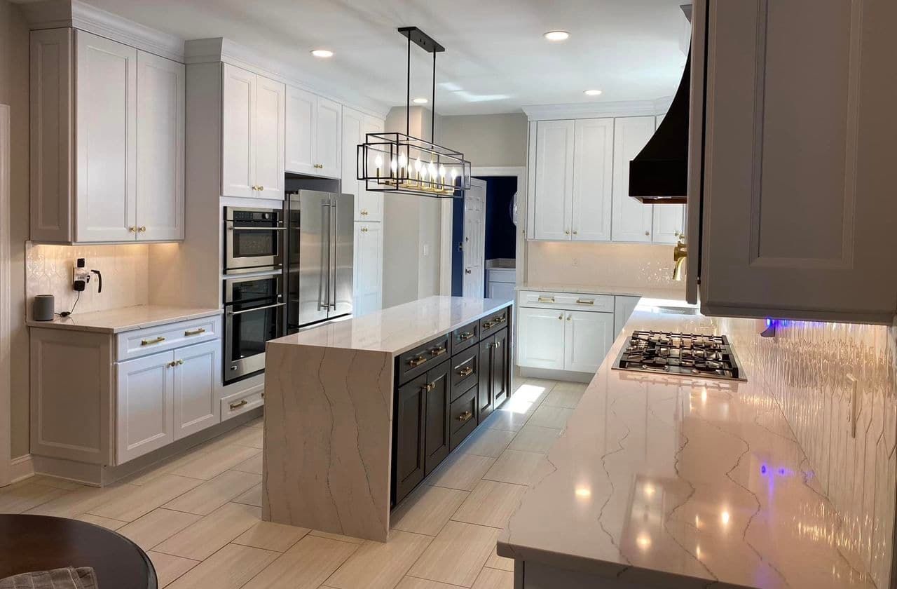A modern kitchen with white upper cabinets, a contrasting dark island and vent hood, and light wood-tone flooring.