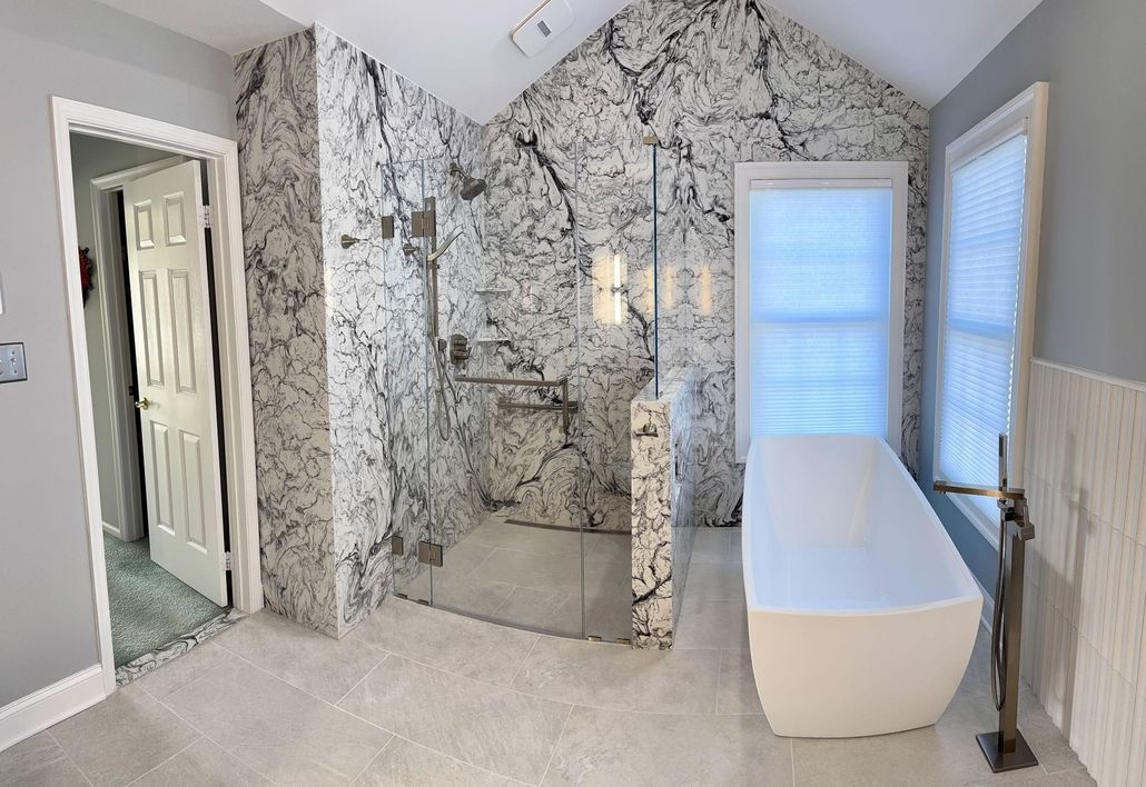 A modern bathroom featuring a freestanding tub and a glass-enclosed shower with bold, black-and-white marble-style tiling.