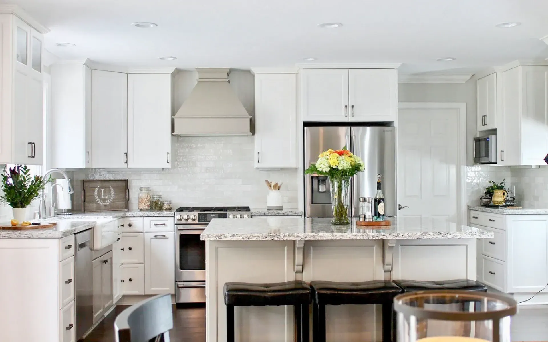 Bright, modern kitchen with white cabinets, stainless steel appliances, a center island with stools, and subway tile.