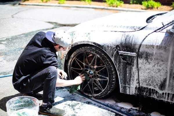 A man is kneeling down to wash a car.