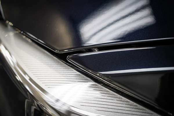 A close up of a car 's headlight and hood.