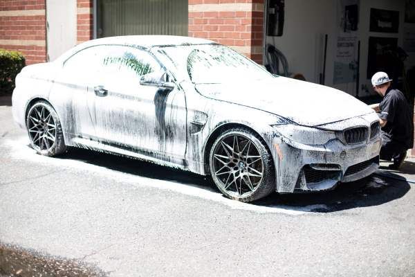 A man is cleaning a bmw m4 with foam.