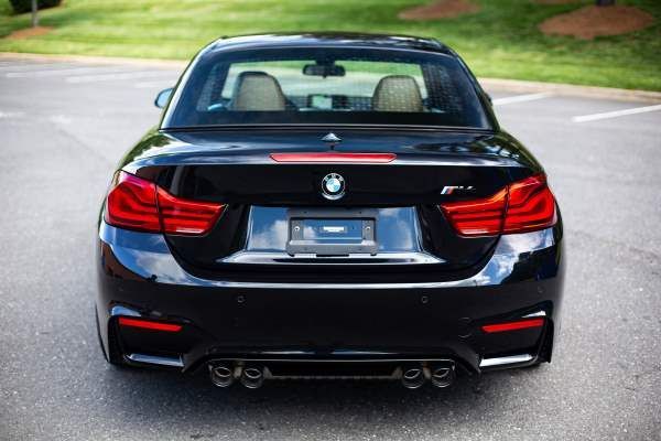 A black bmw convertible is parked in a parking lot
