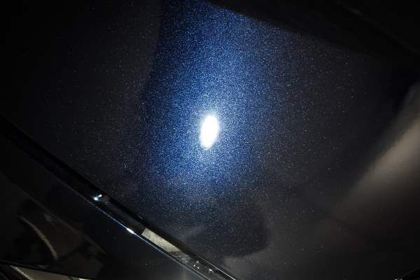 A close up of a blue car hood with a light shining on it.
