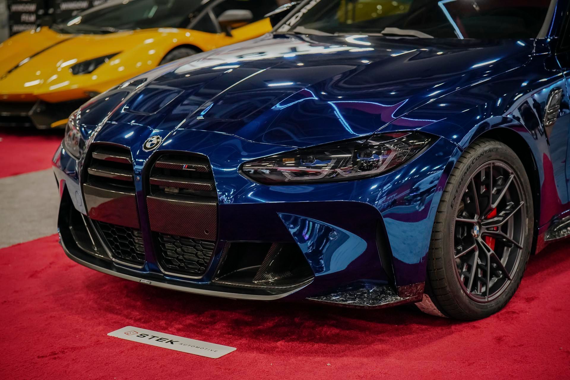 A man is standing next to a green car in a garage.