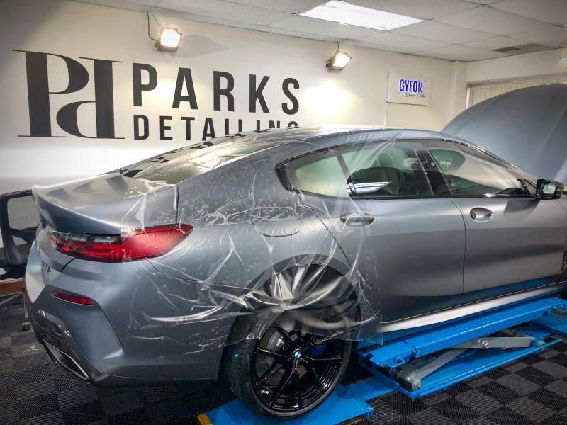 A car is wrapped in plastic and sitting on a lift in a garage.