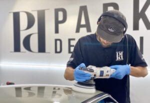 A man is polishing a car with a machine.