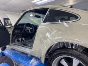A white car is covered in plastic wrap in a garage.