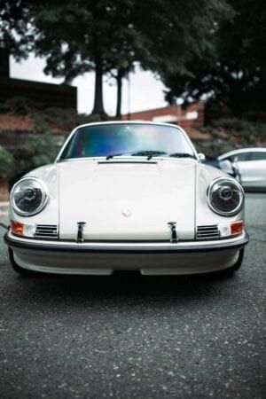 A white porsche 911 is parked on the side of the road.