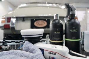 A car is sitting in a garage next to a bottle of polish.