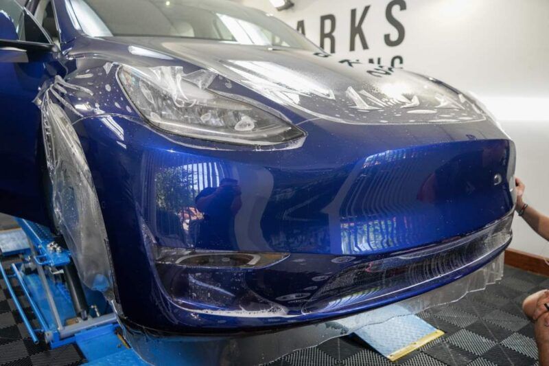 A tesla model y is being protective filmed in a garage.