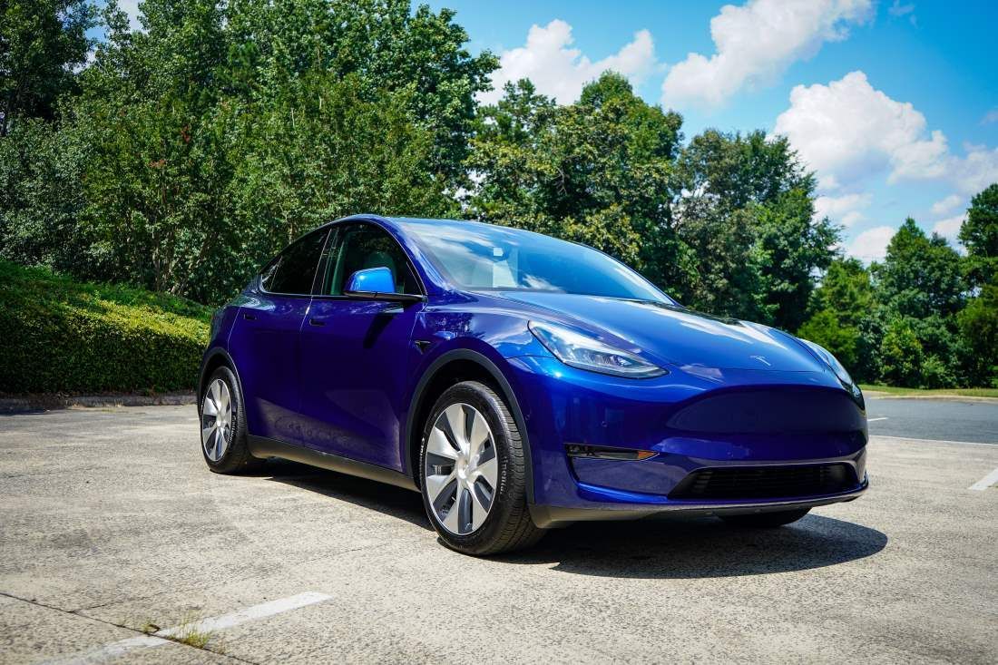 A blue tesla model y is parked in a parking lot.