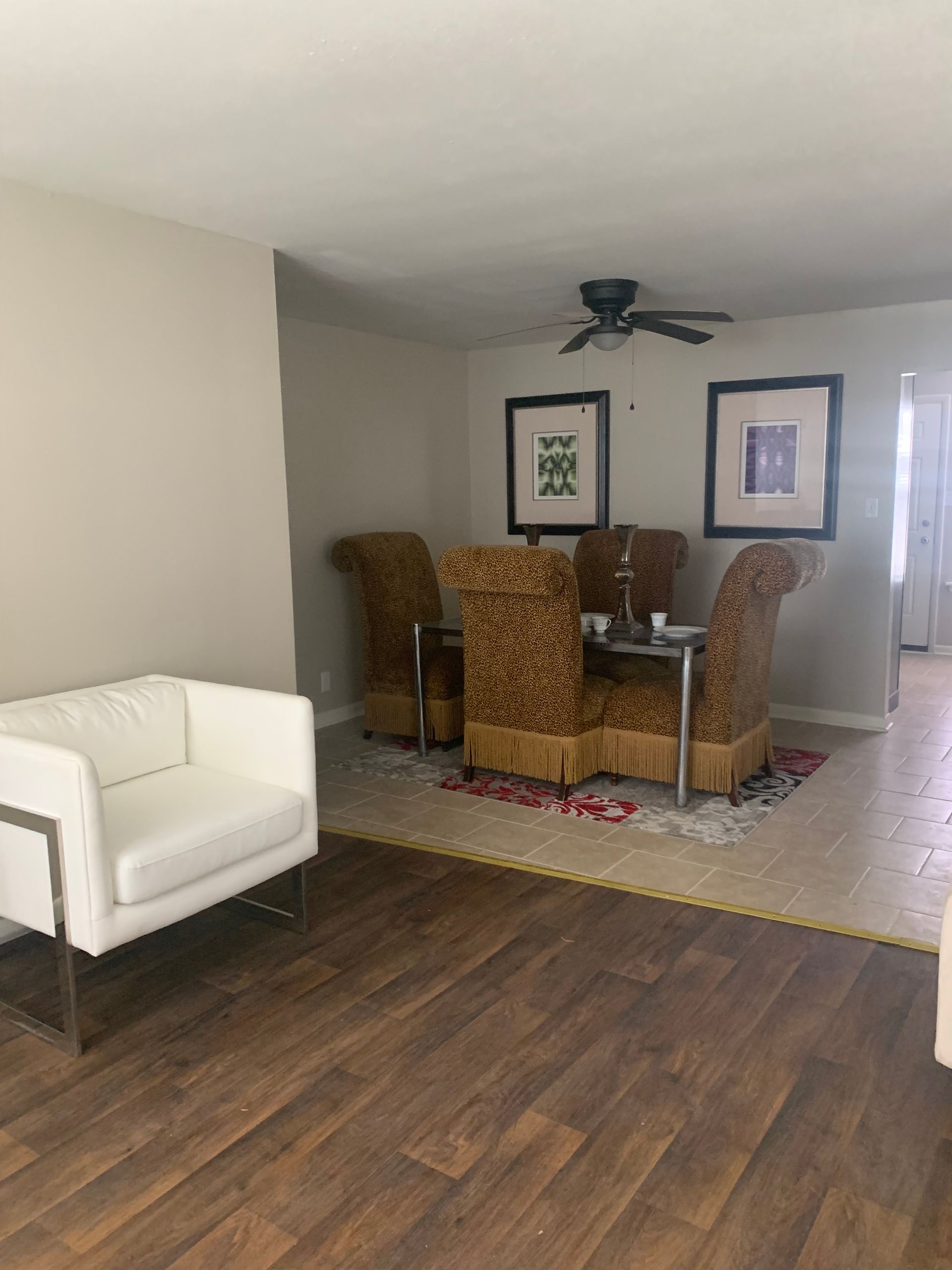 Living room with white chair, dining table, and brown flooring.