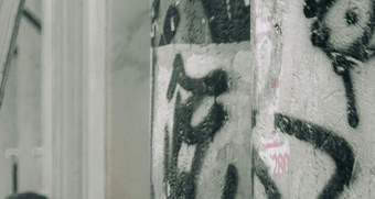 Graffiti on concrete pillar in urban setting; black and white.