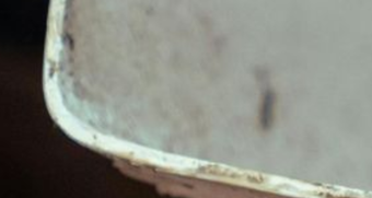 Close-up of a worn, dirty, white metal bucket with a rounded edge.