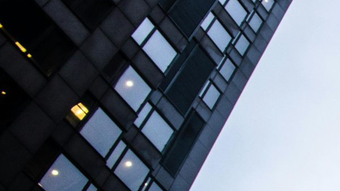 Dark modern building with many windows against a gray sky.