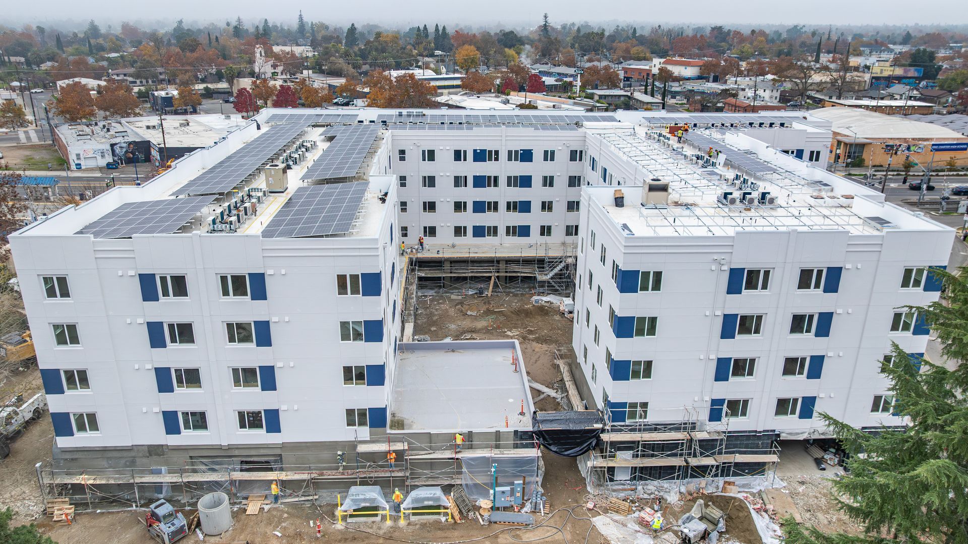 Aerial view of a modern white apartment complex under construction in a snowy neighborhood
