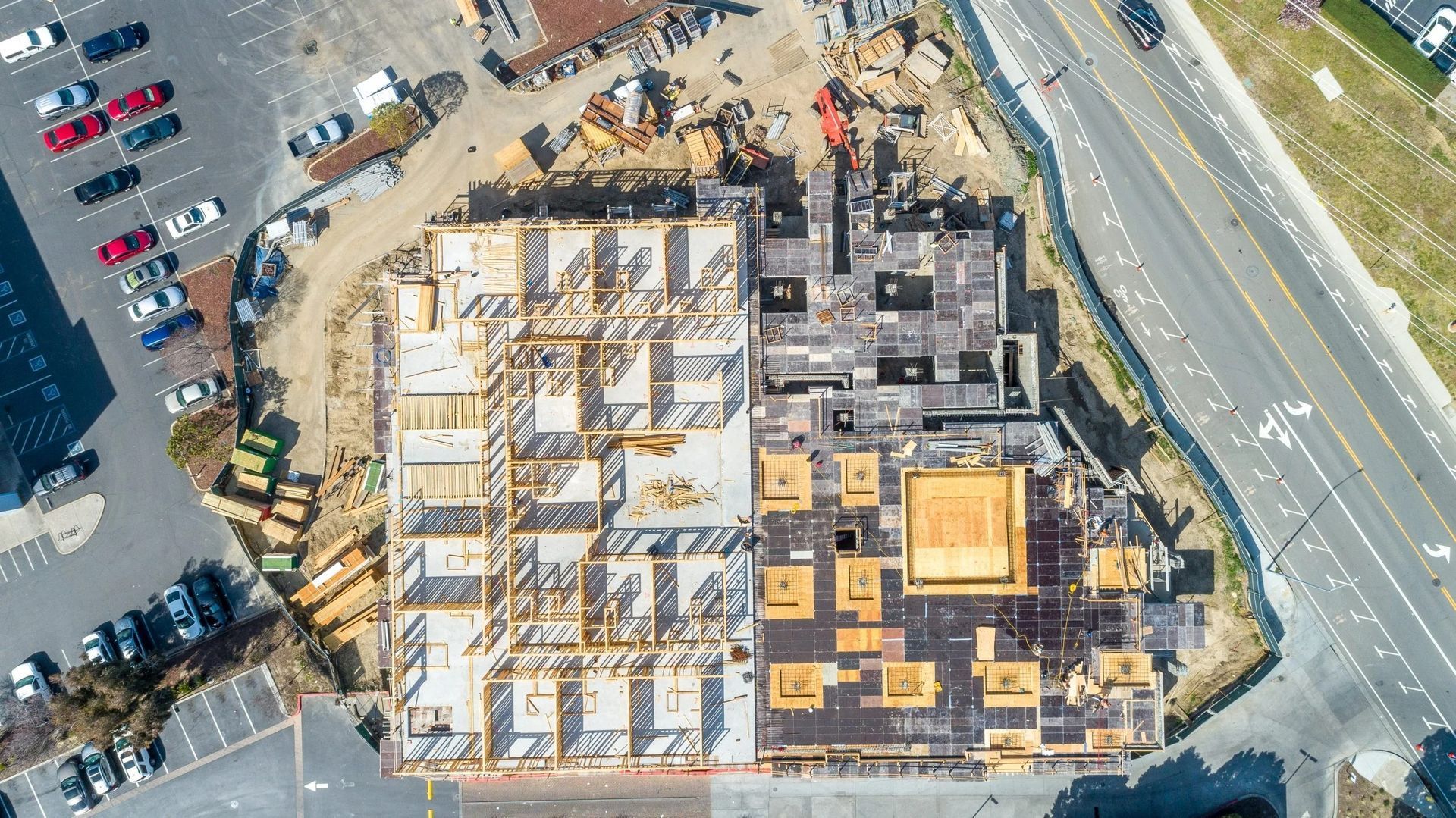 Aerial view of a rectangular building construction site featuring exposed wooden framing.