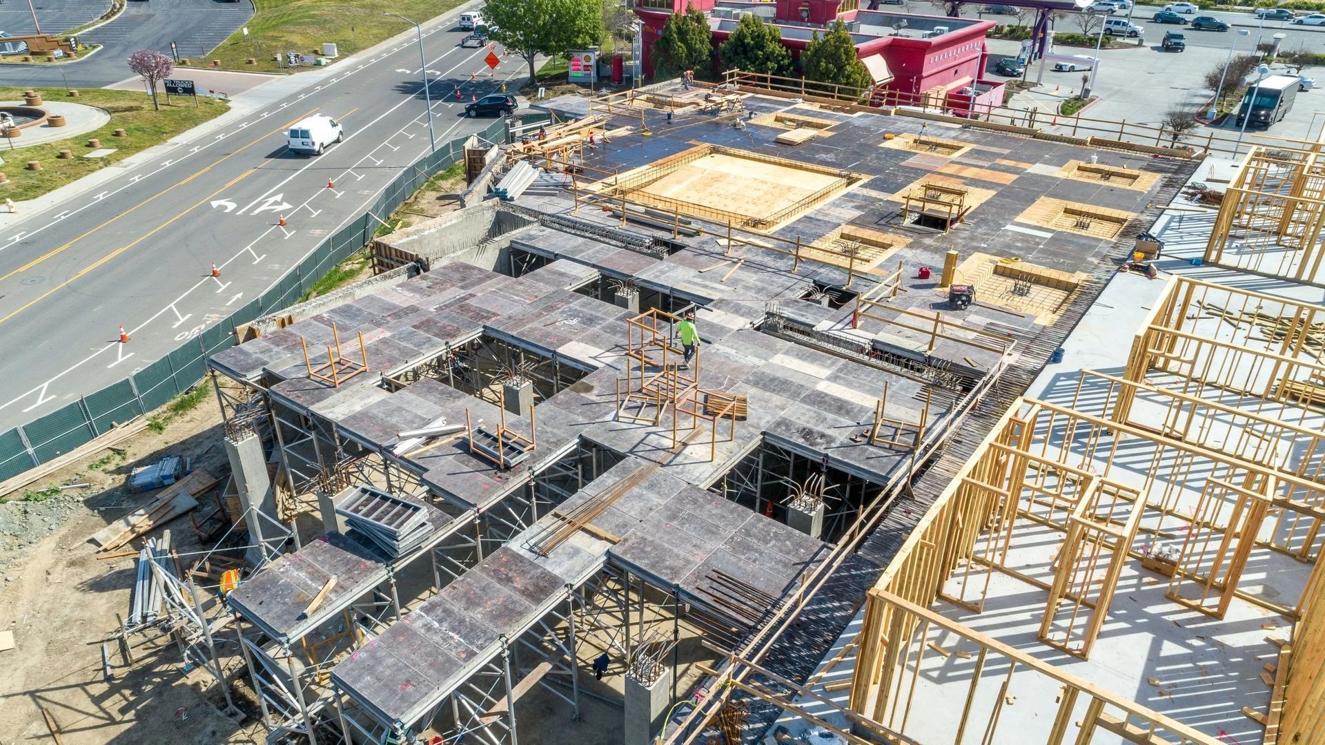 An aerial view of a multi-level construction site featuring concrete slabs, and wooden framing.