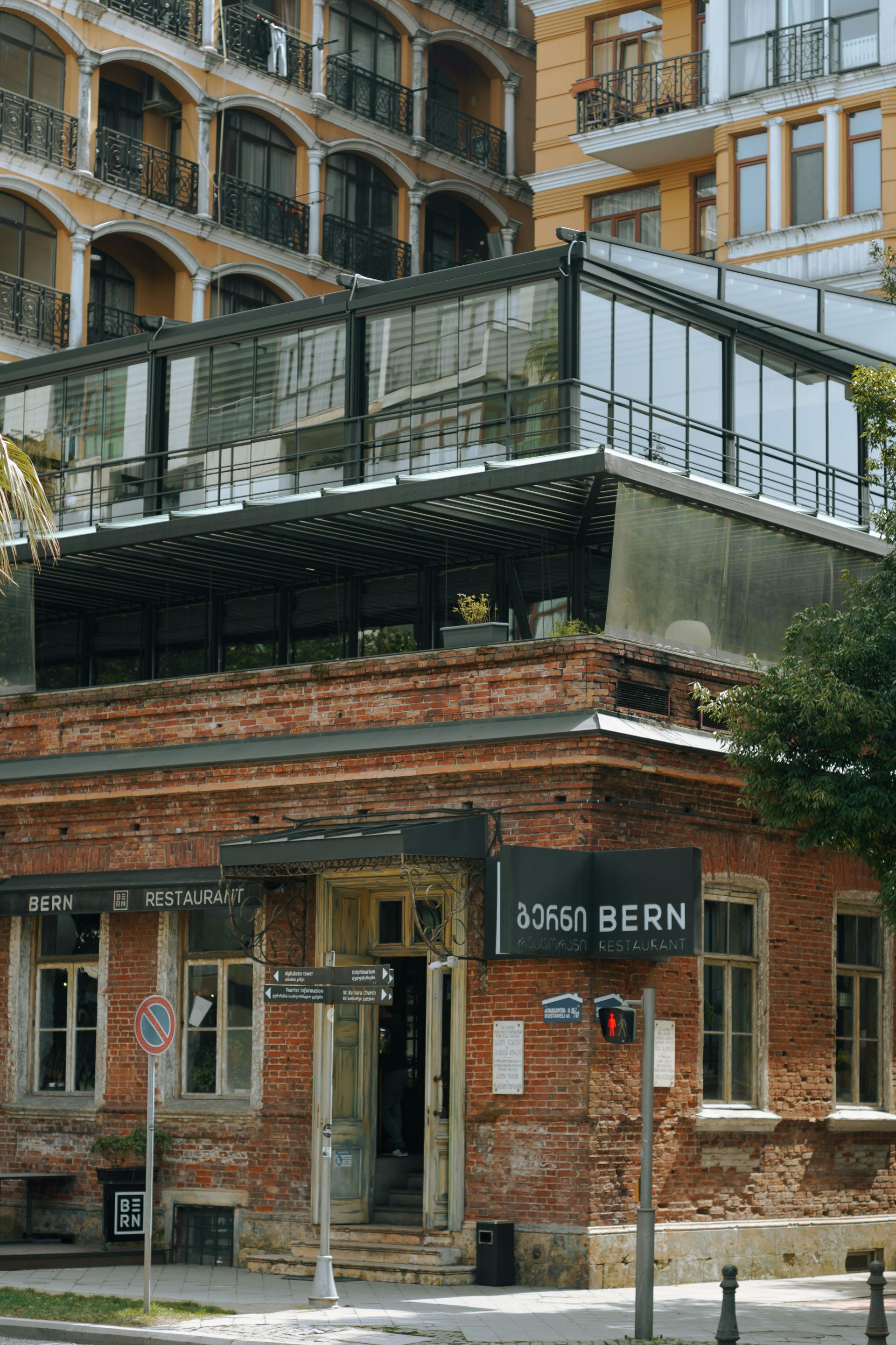A brick building with a modern glass extension on its roof, housing a restaurant labeled 