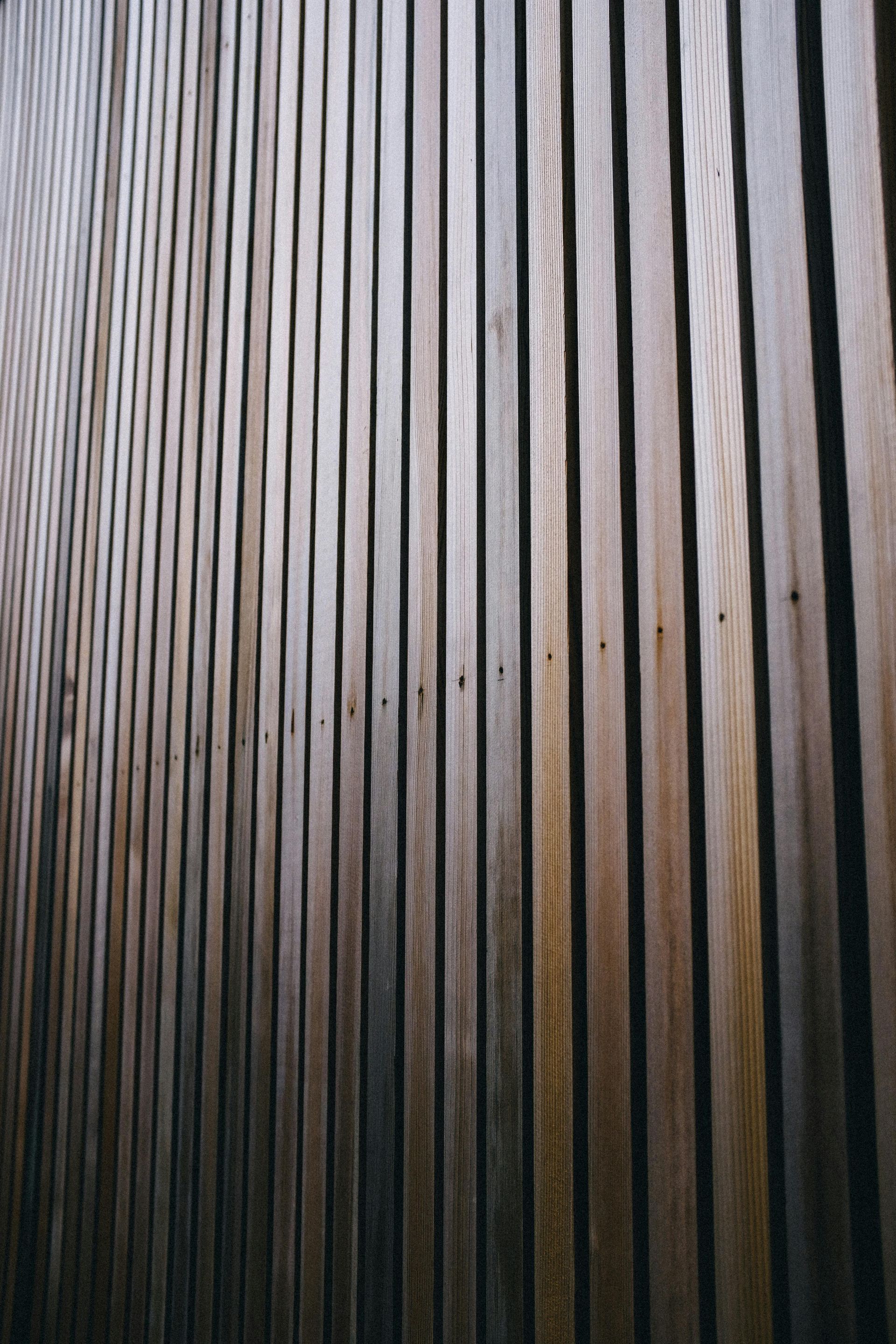 Vertical wooden slats forming a wall, with visible fasteners aligned across the center.