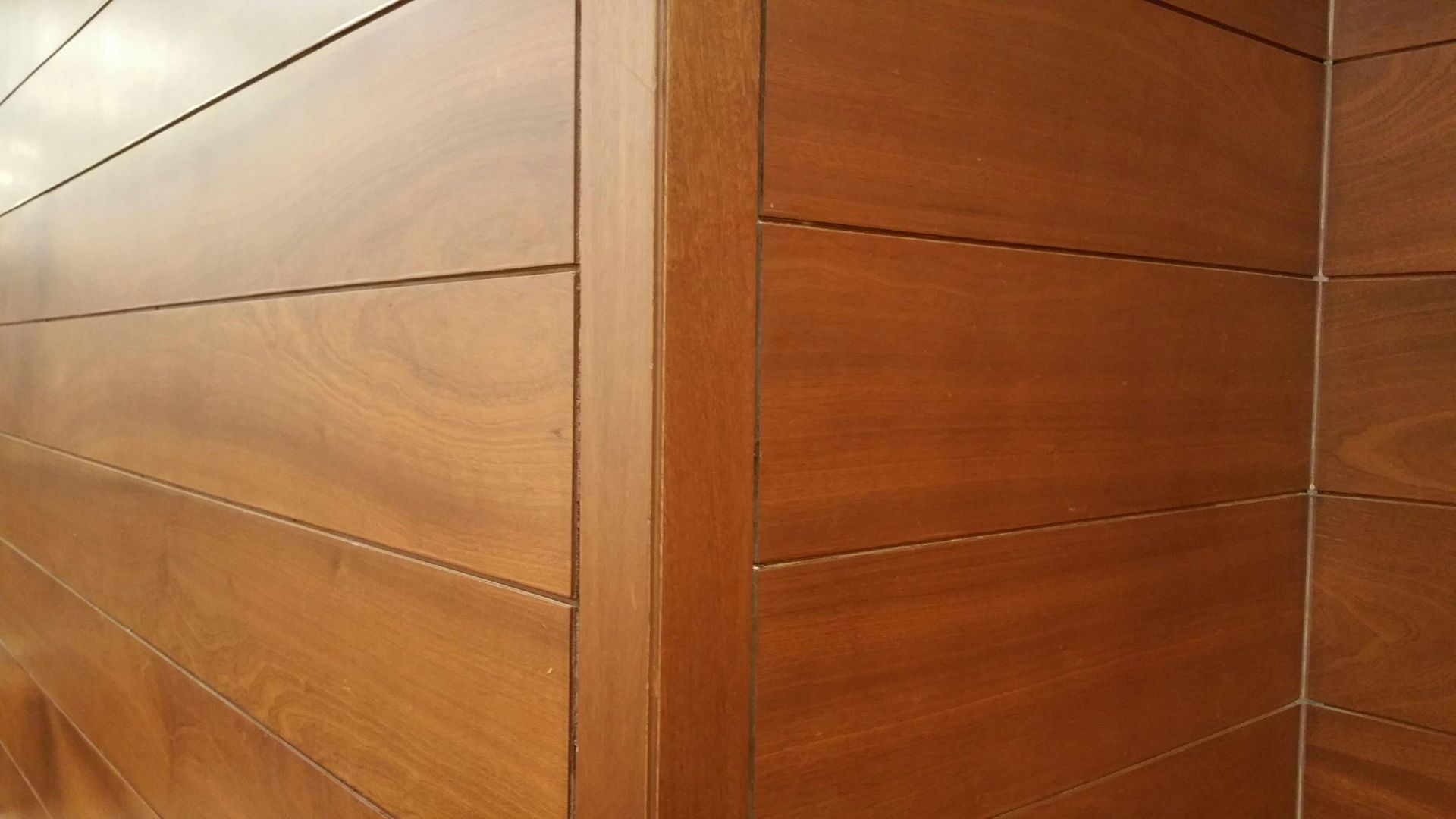 Close-up of a brown wood-paneled wall meeting at a clean corner joint.