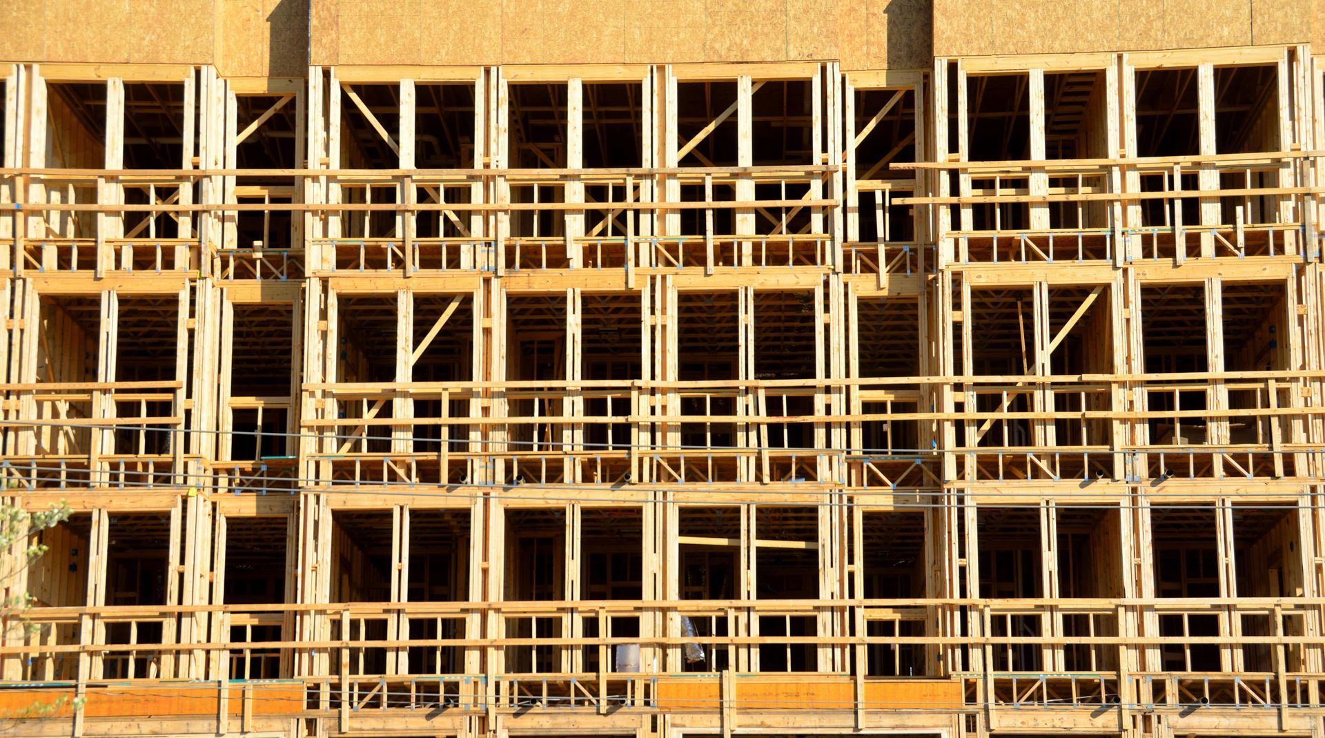 An exterior view of a multi-story wooden building frame under construction.