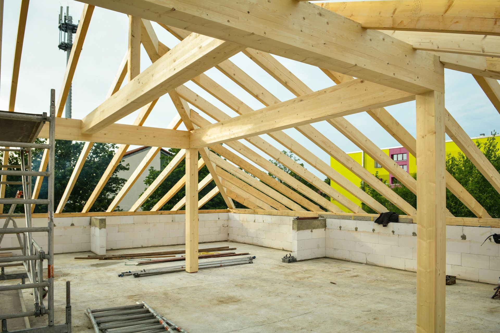 Wooden roof framing structure on a building under construction, viewed from an unfinished attic space.