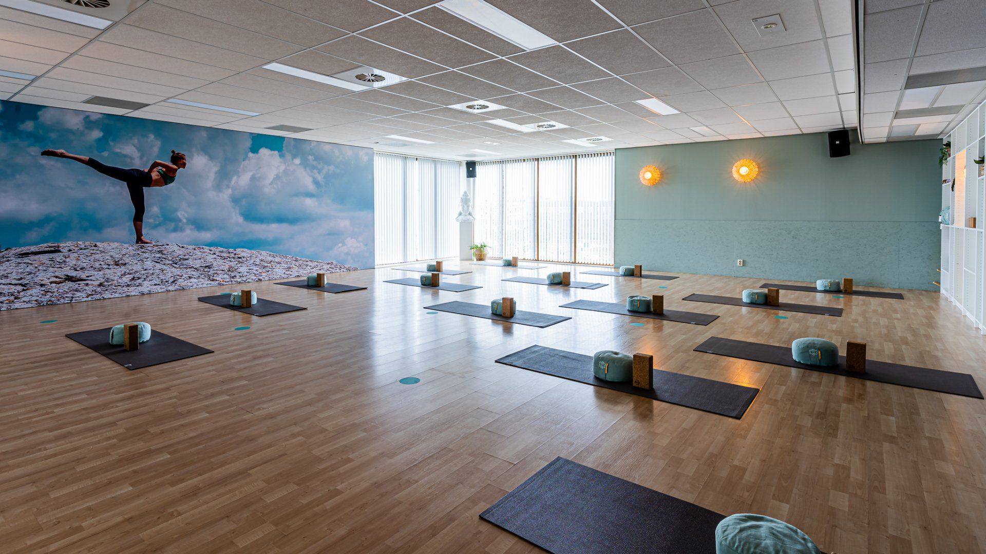 Een grote kamer gevuld met yogamatten en kussens in een yogastudio.