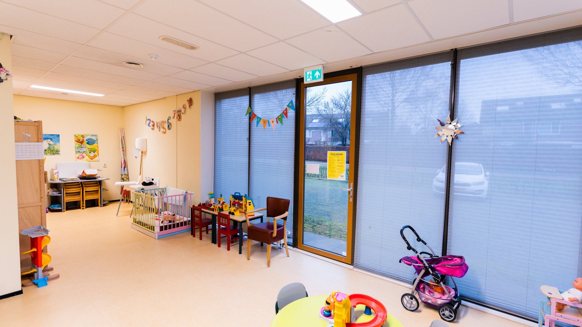 Een kamer met een tafel en stoelen en een kinderwagen erin.