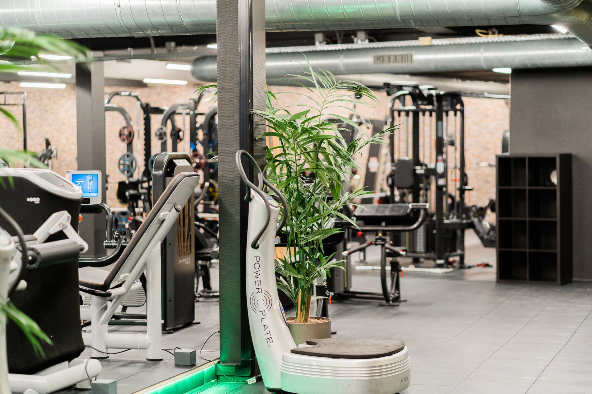 Een sportschool vol met veel fitnessapparatuur en een vibratiemachine.