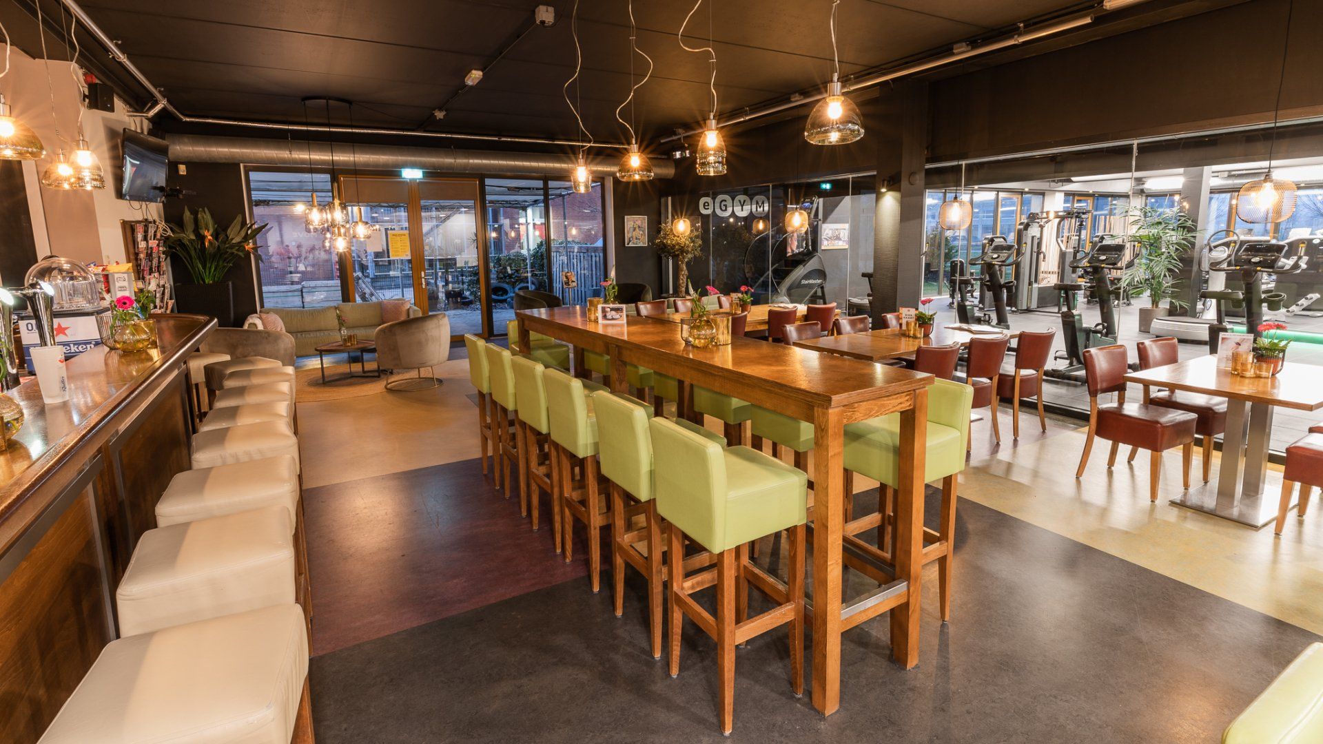 In het midden van de kamer staat een lange tafel met groene stoelen.